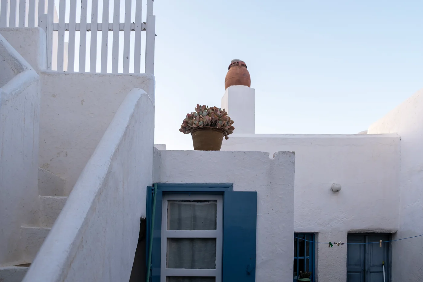 Witgekalkt huis met blauwe luiken en een buitentrap op het Griekse eiland Folegandros